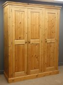 Solid pine triple wardrobe, projecting cornice, three panelled doors enclosing fitted interior,
