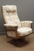 Ercol beech framed swivel rocking chair, upholstered in a floral fabric,