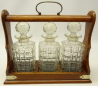 Early 20th century oak three bottle tantalus with silver-plated mounts and brass handle,