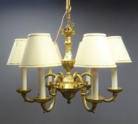 Brass chandelier with carved leaf detailing and six scrolled branches with fabric lampshades