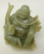 Nephrite carved buddha seated on a lily pad holding a carp,