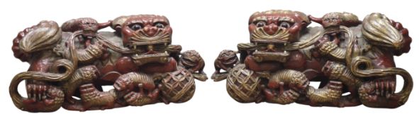 Pair of Chinese carved and red painted wood Temple Lions and cubs, paw resting on a pierced ball,