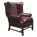 Large 20th century Georgian style wingback armchair, upholstered in buttoned dark brown leather,