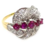 Ruby and diamond scroll ring, five graduating central rubies with diamond surround,