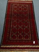 Old Baluchi black and red ground rug, repeating border,