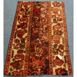 Persian red and beige ground rug, decorated with stylised flower heads,