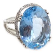 White gold oval blue topaz ring, with diamond halo surround and diamond set shoulders,