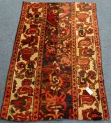 Persian red and beige ground rug, decorated with stylised flower heads,