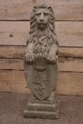 Composite stone seated lion holding crested shield,