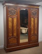 Edwardian walnut triple wardrobe, projecting cornice above two doors carved with urns and flowers,