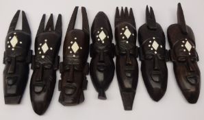 Six carved hardwood African masks representing the days of the week, lacking one,