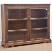 Early 20th century medium oak bookcase, projecting above carved frieze detail, two glazed doors,