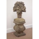 Weathered composite stone garden feature of floral basket on plinth,
