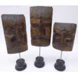 Three 19th century carved oak mask heads on ebonised stands,