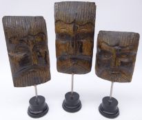 Three 19th century carved oak mask heads on ebonised stands,