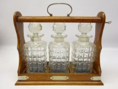 Oak three bottle tantalus with silver-plated mounts,