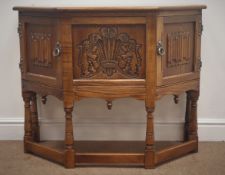 Old Charm oak credence table, canted sides, two carved cupboards doors,