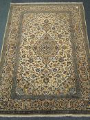 Kashan beige and blue ground rug, central medallion, repeating border,