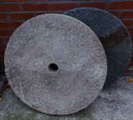 Two circular mill stones, one with cast iron back,