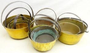 Nine graduating brass jam pans with cast iron handles,