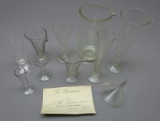 Eight Victorian apothecary's various sized clear glass conical shaped measures with etched