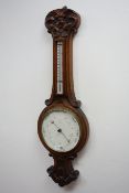 Edwardian carved oak aneroid barometer with thermometer, circular dial signed R.