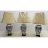 Three Oriental style ceramic blue and white table lamps on ebonised base with shades, as new,