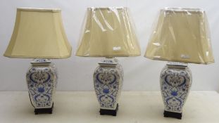 Three Oriental style ceramic blue and white table lamps on ebonised base with shades, as new,