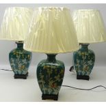 Three Oriental style table lamps decorated with butterflies amongst foliage on turquoise ground on
