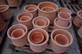 Twenty terracotta cylindrical pots with lattice design,