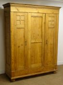 Early 20th century continental triple pine wardrobe, projecting cornice, three panelled doors,