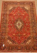 Kashan red ground rug, floral field, repeating border, signed by the weaver,