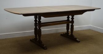 Ercol medium elm extending dining table, four baluster supports joined by stretchers on sledge feet,
