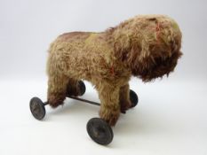 Early 20th century straw filled push dog on wheels,