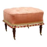 Square footstool upholstered in salmon fabric, deep buttoned top with tasselled fringe,