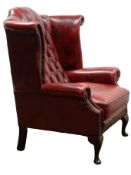 Queen Anne style wingback armchair, upholstered in deep buttoned oxblood red leather,