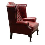 Queen Anne style wingback armchair, upholstered in deep buttoned oxblood red leather,