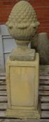 Composite stone pineapple gatepost finial on a pedestal,