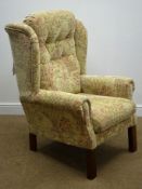 Wingback armchair upholstered in a buttoned floral fabric, scrolled arms, square supports,