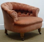 Victorian low tub shaped chair, upholstered in a buttoned pink fabric, turned supports on castors,