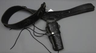 Black leather Mexican single gun rig, belt tooled with scrollwork and chrome buckle,