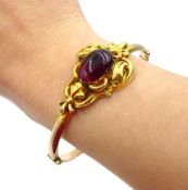 Victorian gold hinged bangle, with an oval cabochon almandine garnet in a scroll setting,