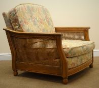 Ercol Bergere standard easy chair, ash frame, cane work sides, upholstered in a floral fabric,