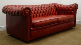 Two seat Chesterfield sofa upholstered in deep buttoned vintage red leather on castors,
