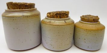 Set of three graduating stoneware jars with cork lids, indistinctly signed,