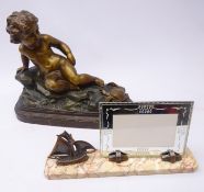Bronzed moulded plaster group of a cherub reclining on a rock apprehensively watching an