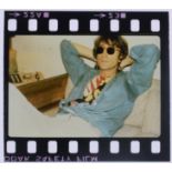 An original 35mm transparency of John Lennon relaxing in a hotel room beside a pink telephone.