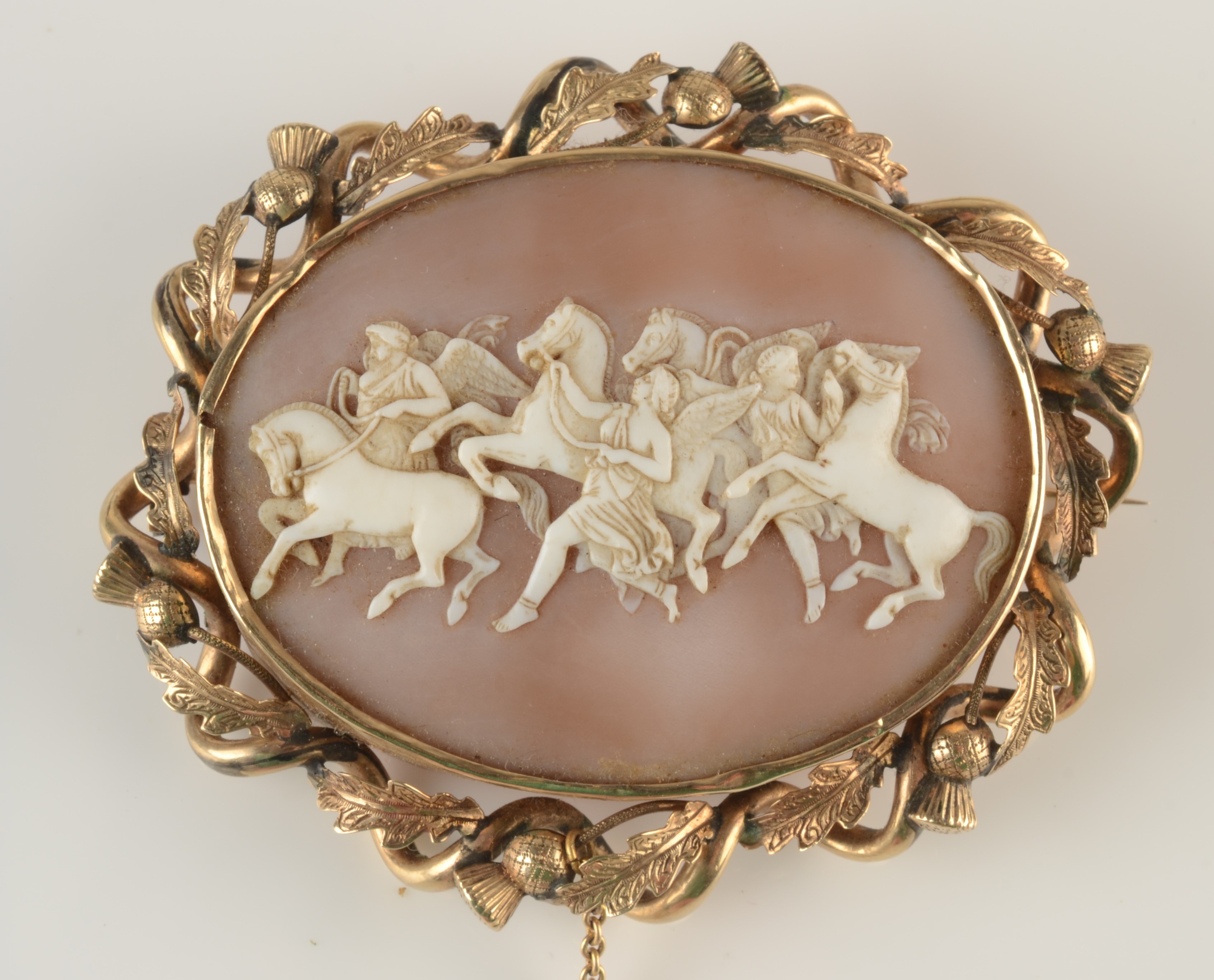 A 19th century large oval cameo brooch showing wild horses and mythical figures in a gold thistle