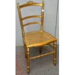 An early 20th century gilt decorated bedroom chair, with a cane seat on turned legs, height 86cm.