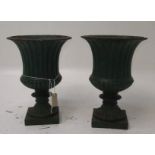 A pair of green painted cast iron urns, of campana form on square feet, height 46cm, diameter 34cm.
